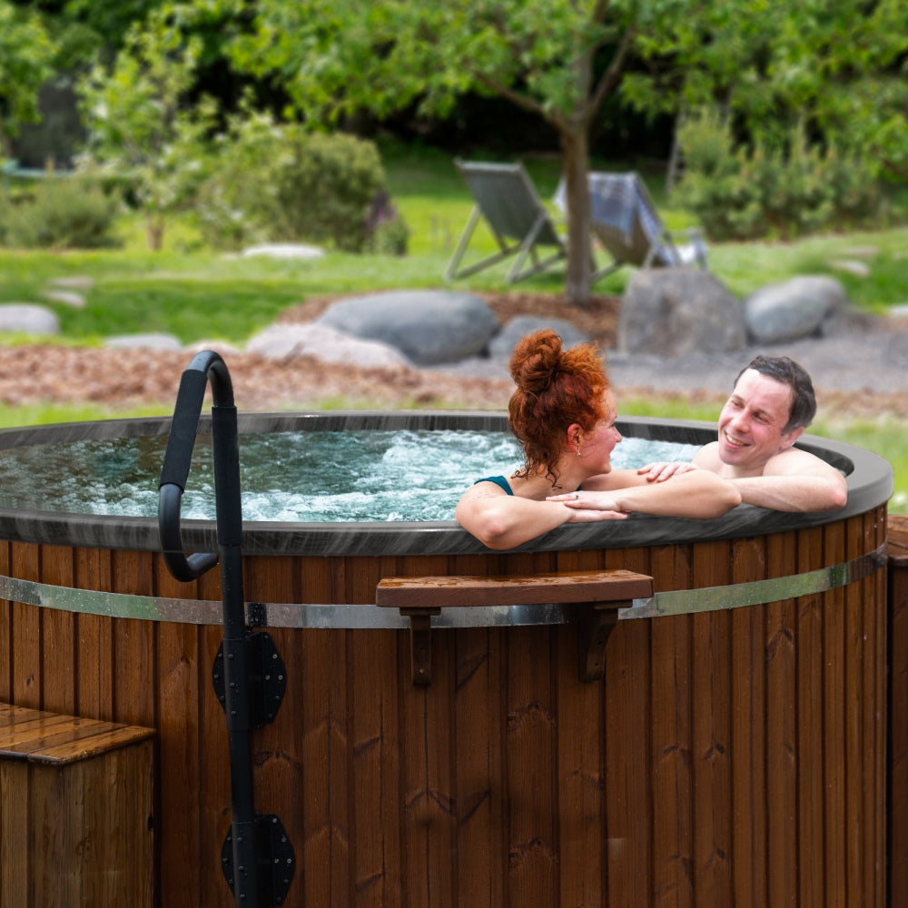 Couple relaxing in a configured 4-6 seater wood fired hot tub with integrated heater outdoors