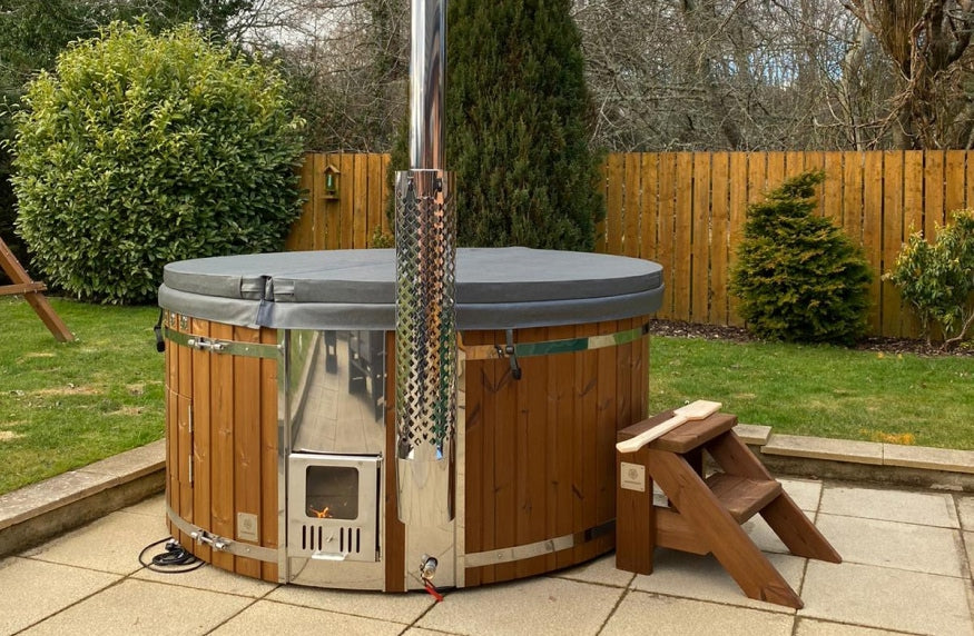 A round hot tub covered by a lid on the terrace, featuring standard steps and a integrated stove