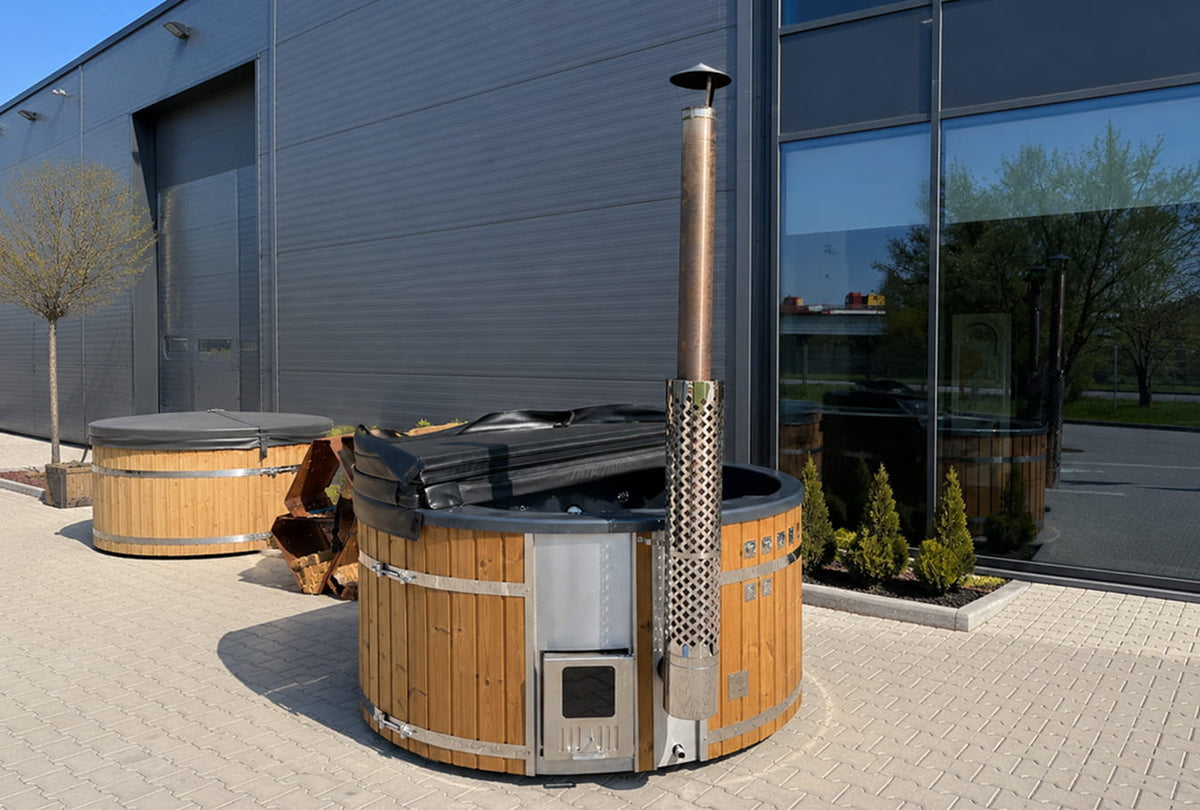 Wood-fired hot tubs outside a modern building with large windows.