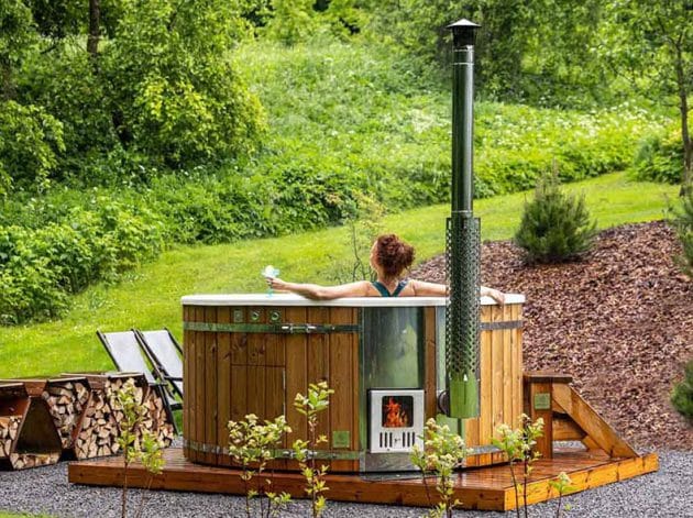 A woman relaxing in a Gardenvity wood-fired hot tub in the nature