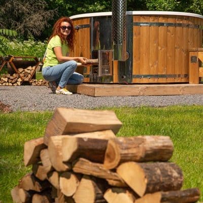 A wood-fired hot tub with firewood for heating