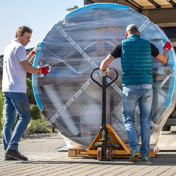 A Gardenvity wood-fired hot tub in its packaging being moved on a pallet truck.