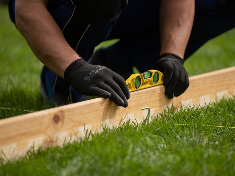 Using a spirit level when preparing the base for a Gardenvity wood-fired hot tub.